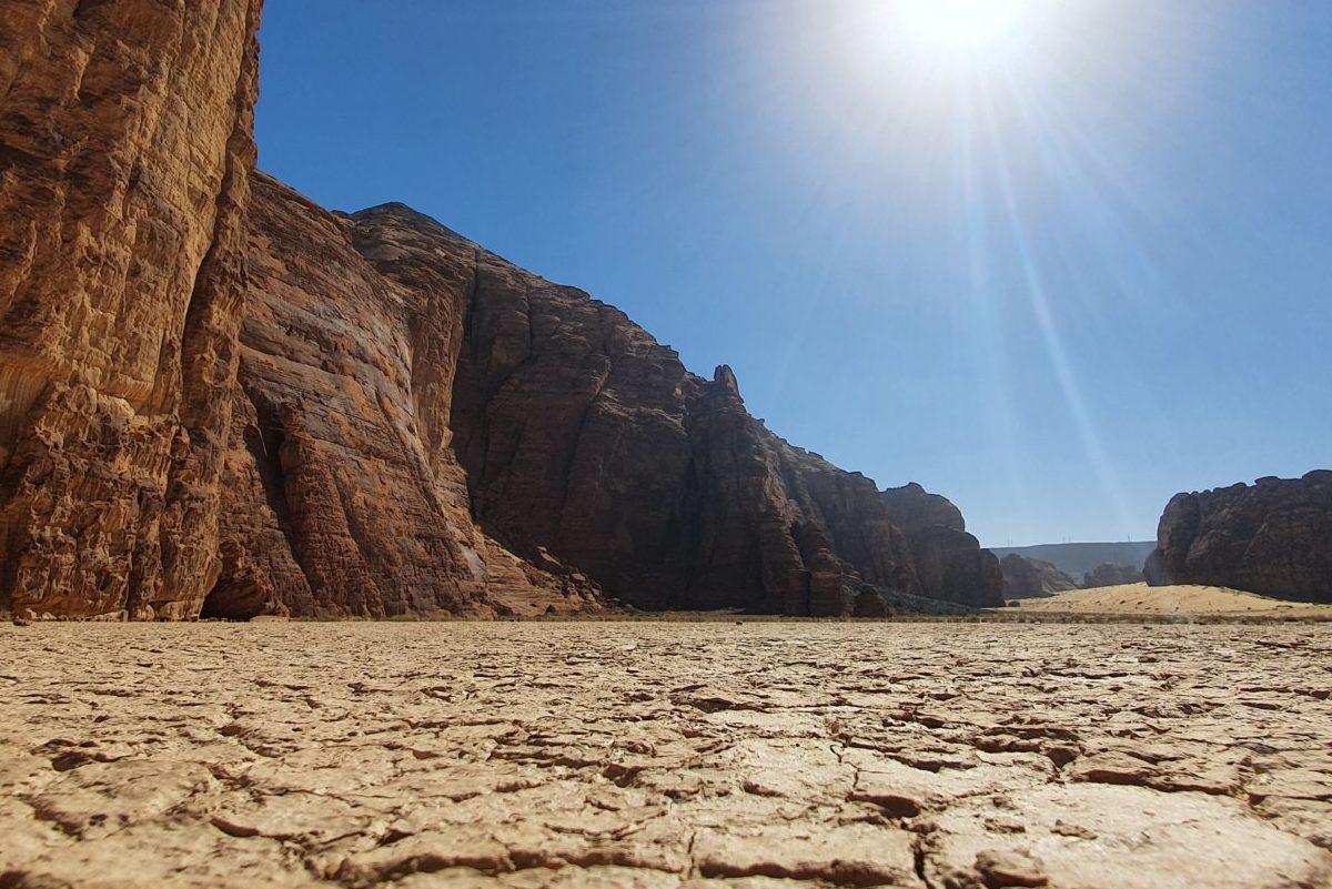 Sun beaming over dry, cracked soil and rock landscape