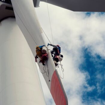 Two workers on a wind turbine in Kaliakra, Bulgaria, September 2020. Power systems must change on the path to net zero. Photo via Adobe.