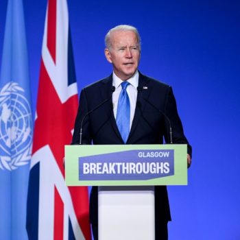 US President Joe Biden talks behind a podium with Glasgow Breakthroughs written on the front, behind him is a union jack flag and the flag of the UN. He wears a dark suit with blue tie and is speaking at the Innovation event for COP26 at the SEC, Glasgow. 02-11-2021.
