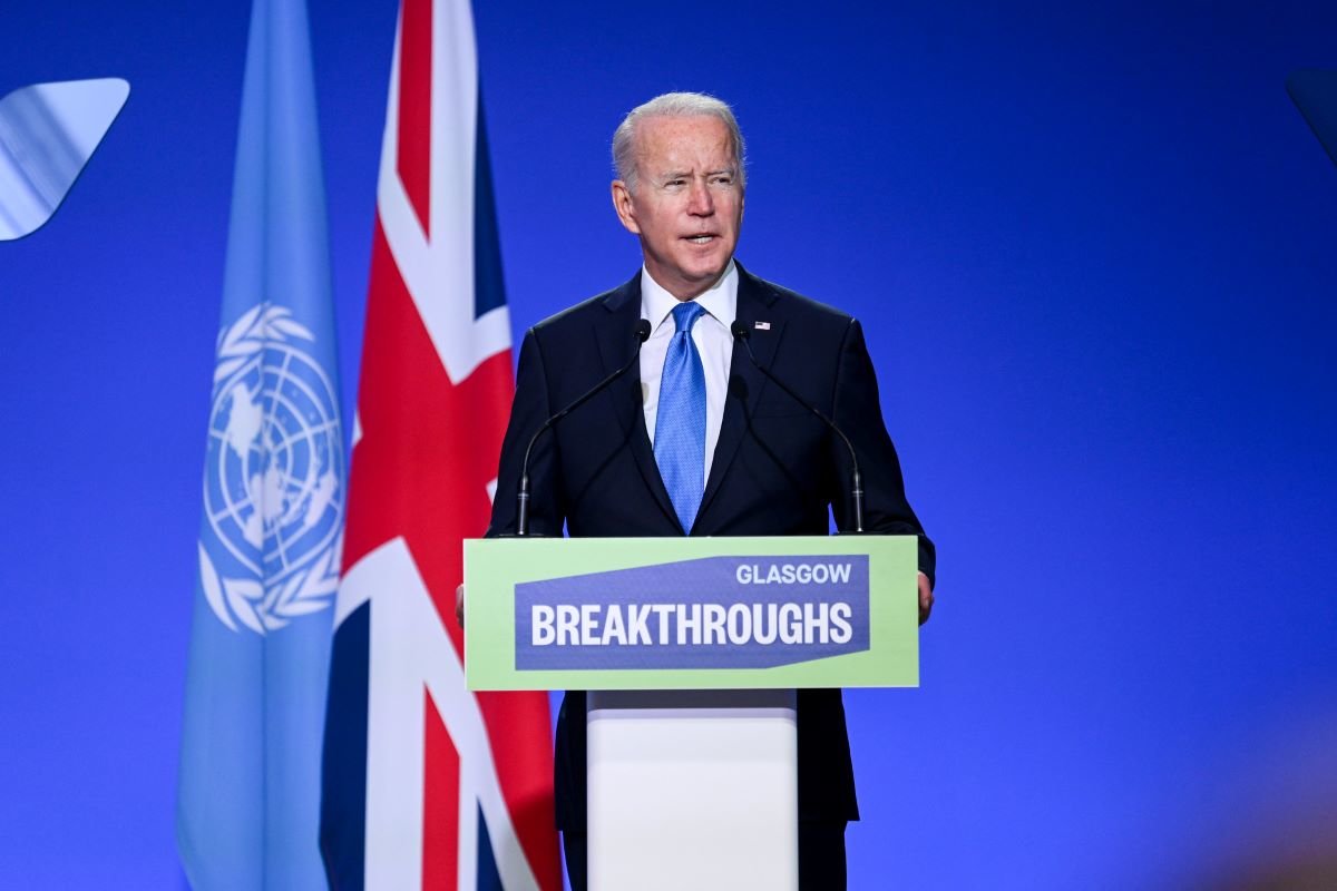 US President Joe Biden talks behind a podium with Glasgow Breakthroughs written on the front, behind him is a union jack flag and the flag of the UN. He wears a dark suit with blue tie and is speaking at the Innovation event for COP26 at the SEC, Glasgow. 02-11-2021.