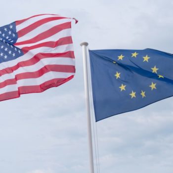 US and EU flags waving against a grey sky