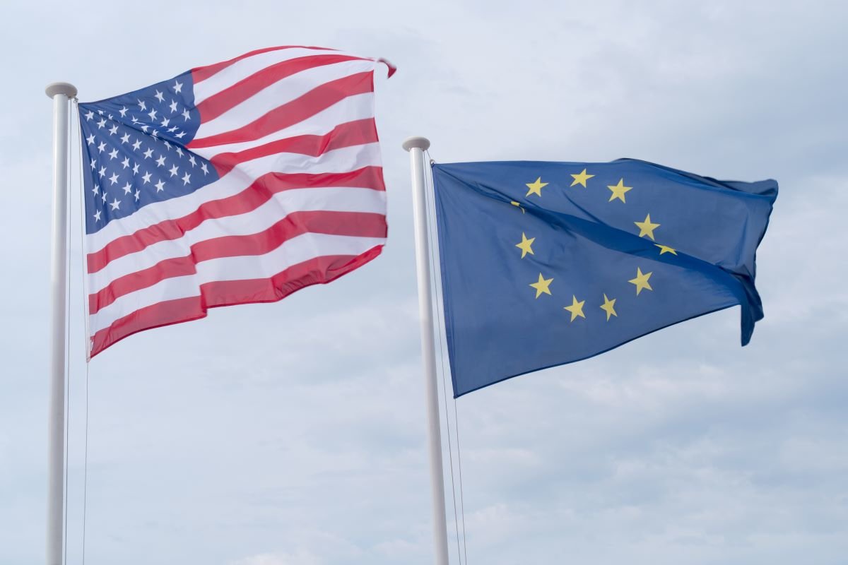 US and EU flags waving against a grey sky