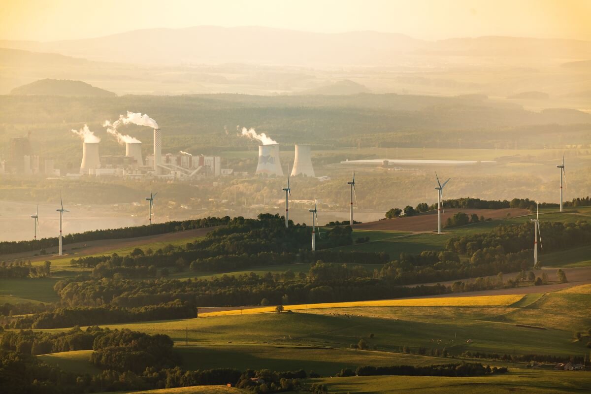 Wind turbines set against backdrop of coal power plant.