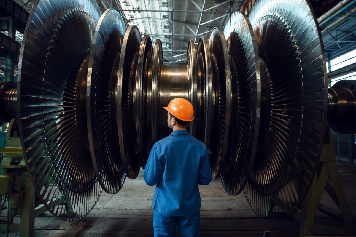 Worker checks turbine impeller vanes in a factory. Photo via Adobe.