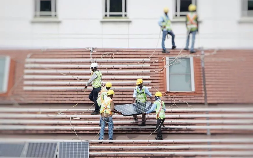 Workers install solar panels on a rooftop