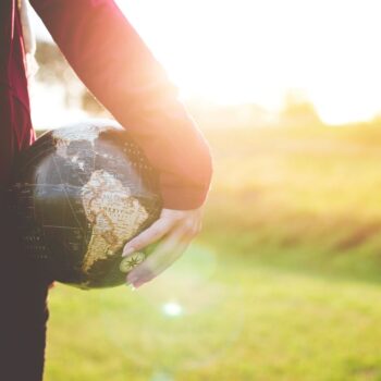 person holding a world globe in their hand in green field