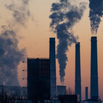 Carbon fumes coming out of a cluster of cooling towers at sunset