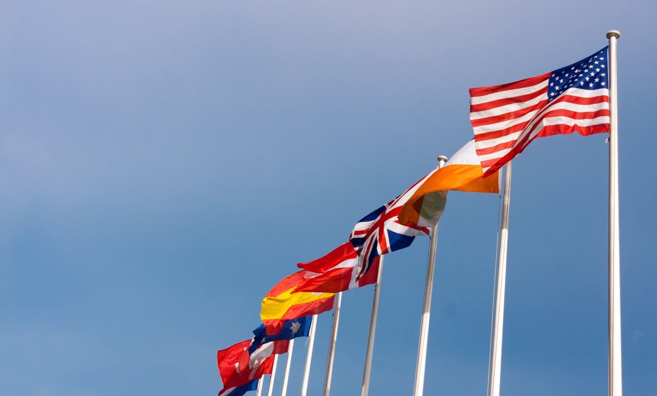 International US and global flags on blue sky