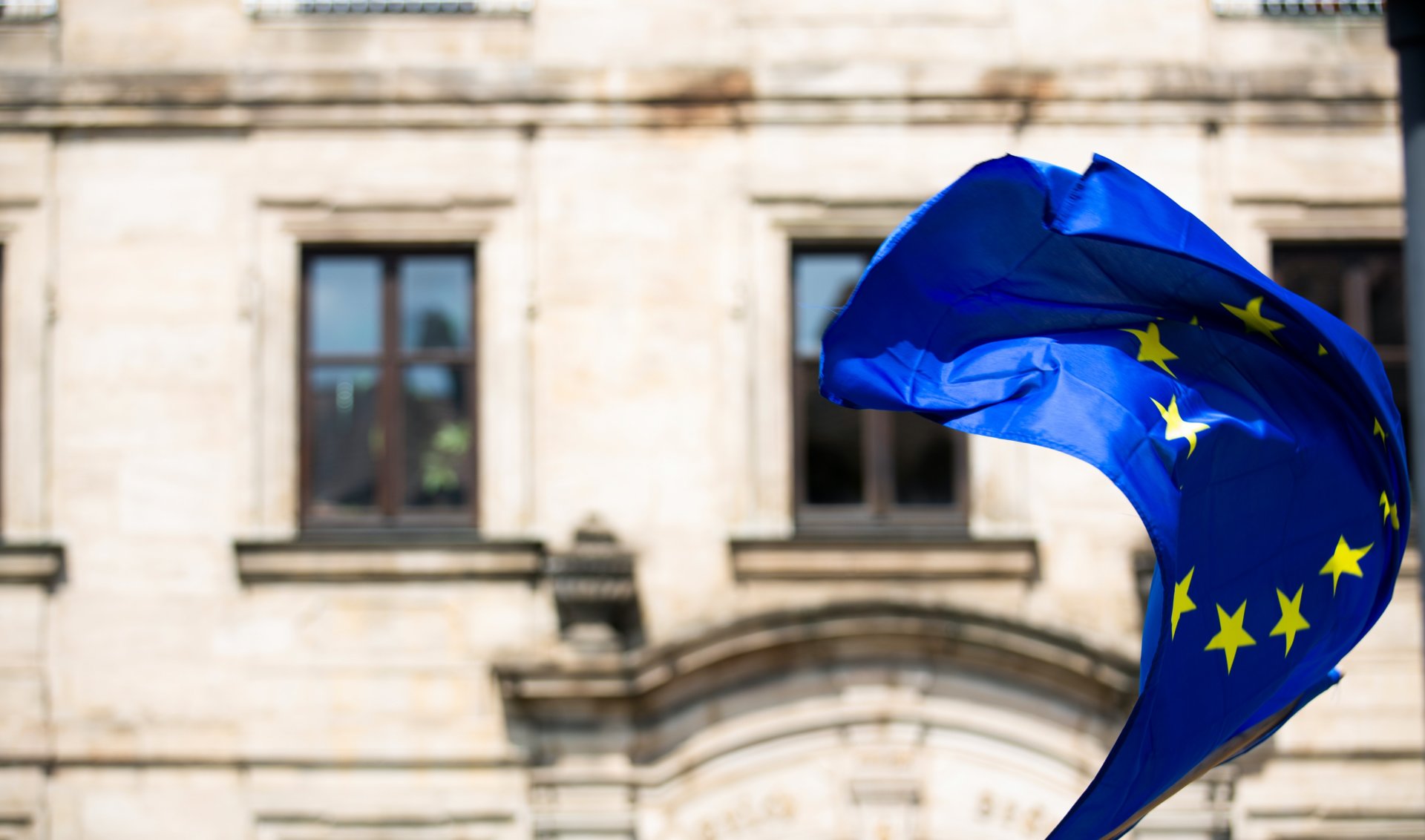 EU flag waving behind a stone building