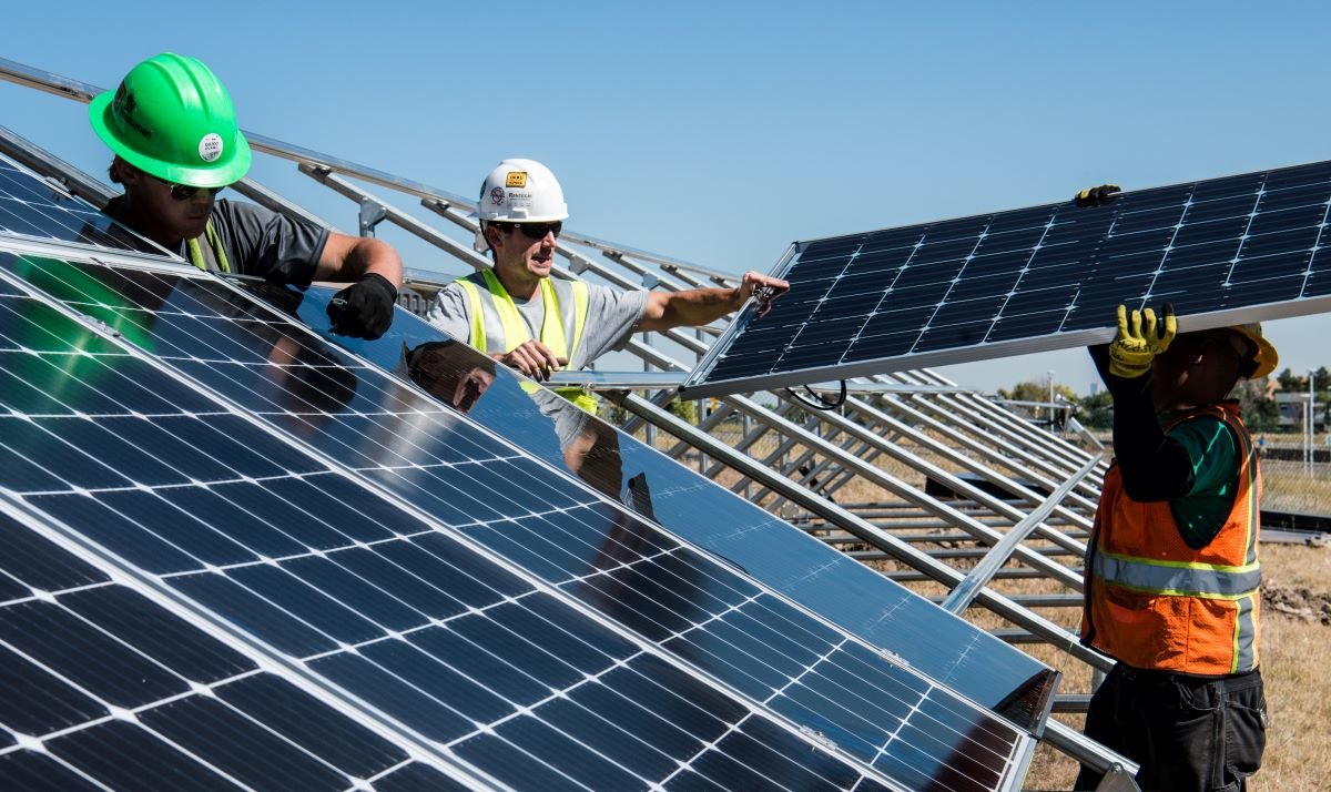 Workers install row of solar panels