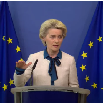 The image shows the President of the European Commission, Ursula von der Leyen, presenting the RePowerEU at a press conference with two european flags behind her.