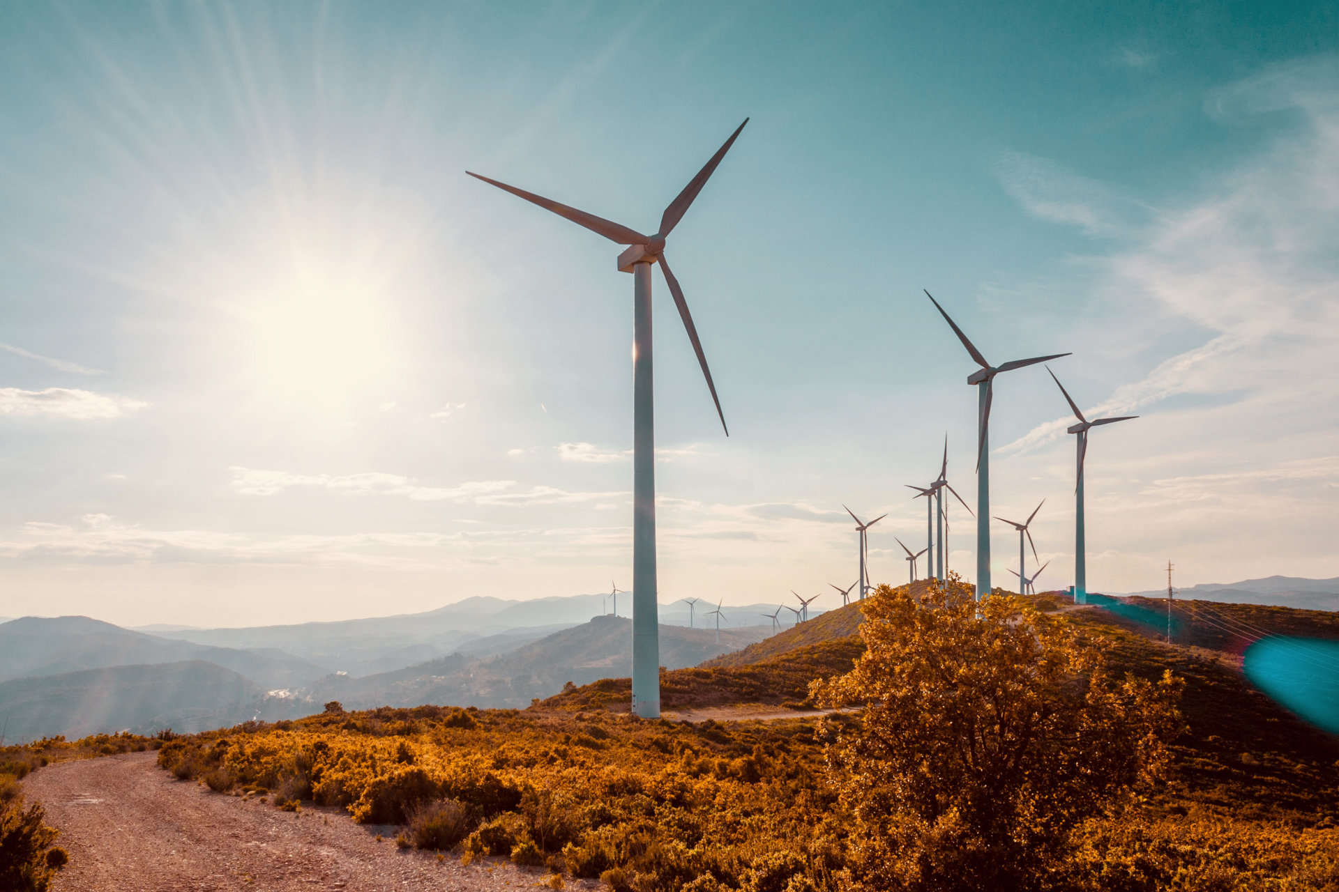 Wind turbines on beautiful sunny summer autumn mountain landsape. Curvy road through mountain Eolic park. Green ecological power energy generation. Wind farm eco field