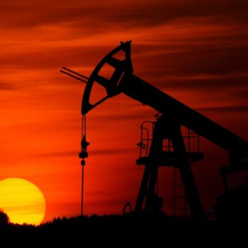 Pump-jack mining crude oil with the sunset.